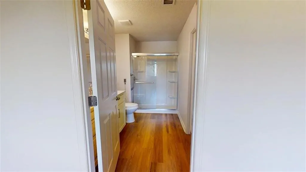 Bathroom with vanity, a shower stall, light wood-style floors, and a textured ceiling