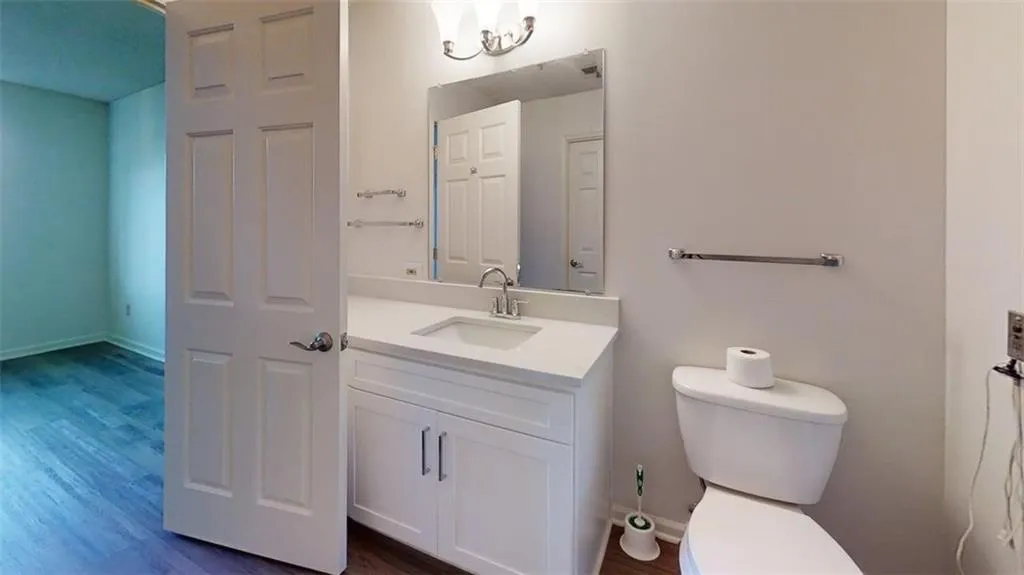 Half bathroom featuring vanity and dark wood-style flooring