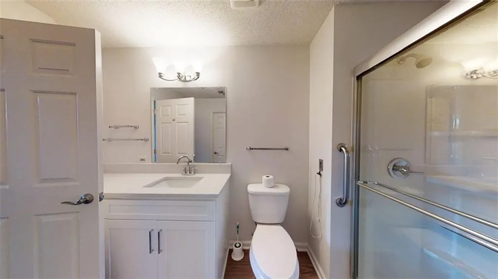 Bathroom with vanity, a textured ceiling, a stall shower, and dark wood finished floors