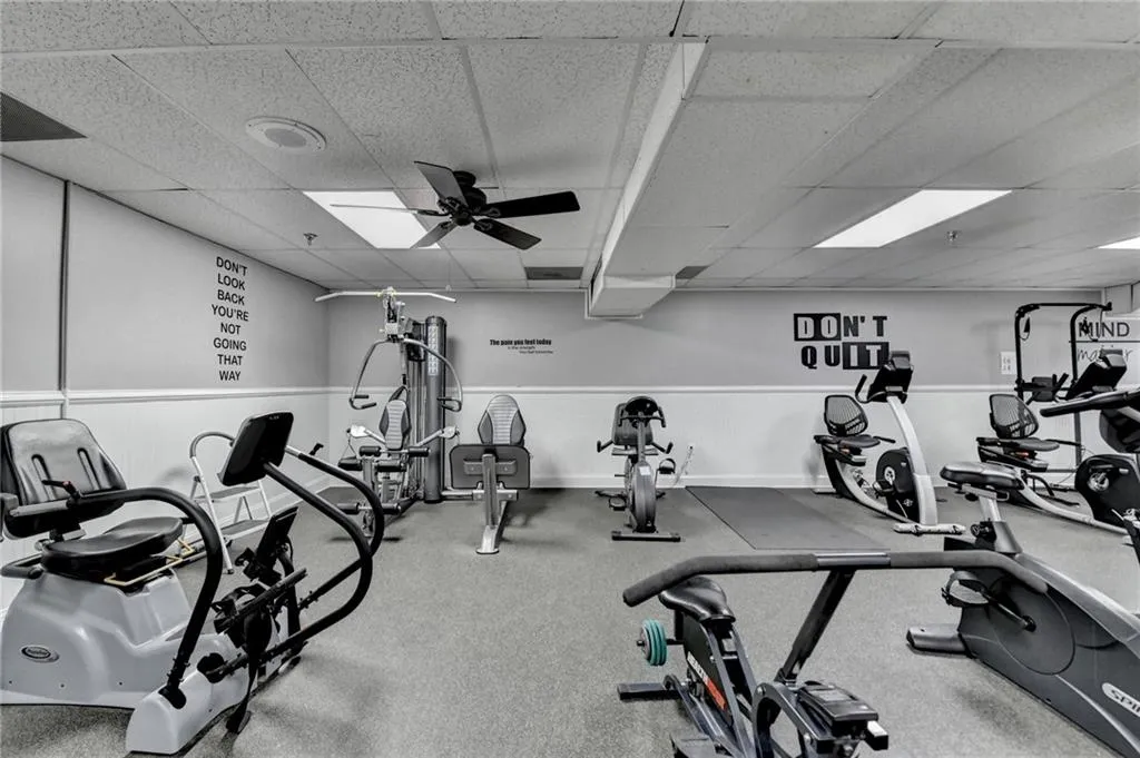 Workout area with a drop ceiling and ceiling fan