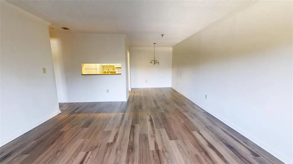 Unfurnished room with dark wood finished floors, a chandelier, and ornamental molding