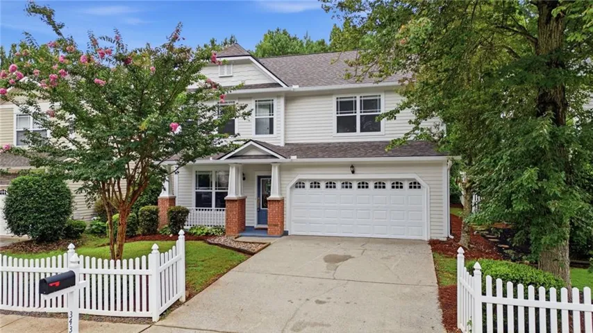 Two-story residence with a two-car garage, white siding, and a covered front porch with brick pillars