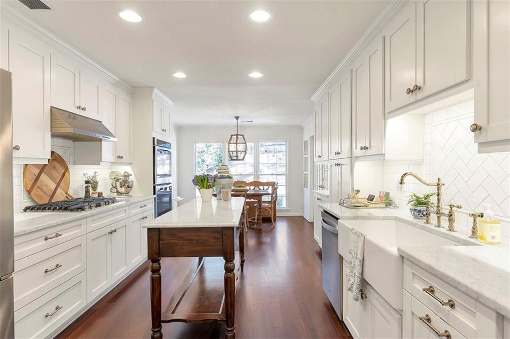 Kitchen featuring tasteful backsplash, hanging light fixtures, dark wood-type flooring, and appliances with stainless steel finishes