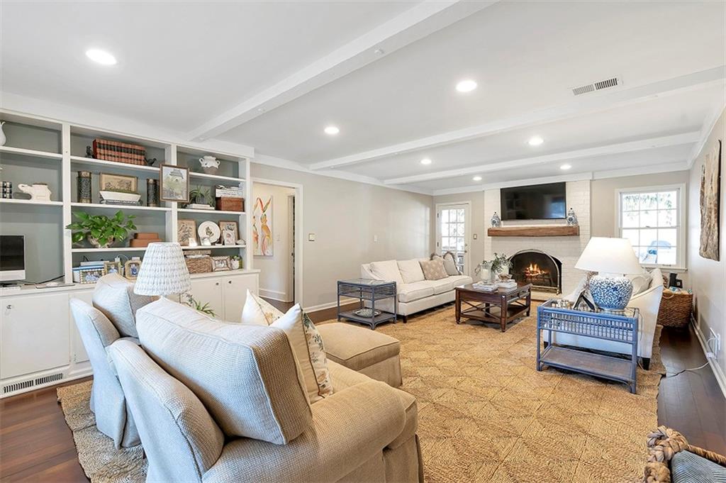 Living room featuring light wood-type flooring, beam ceiling, and a fireplace