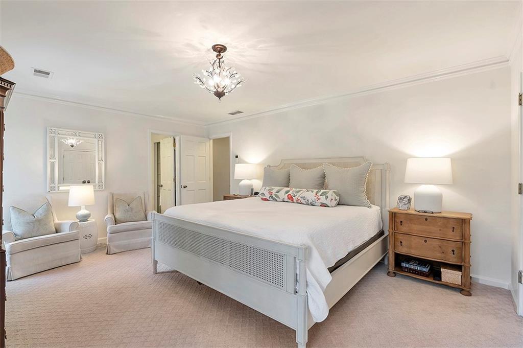 Bedroom with an inviting chandelier, crown molding, and light carpet