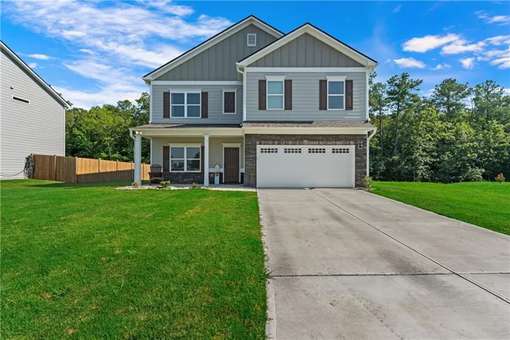 Two-story exterior featuring a stone accent façade, covered porch, attached two-car garage, and concrete driveway