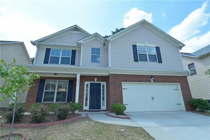 Two-story residence featuring a brick and siding exterior, a two-car garage, and a covered front entry