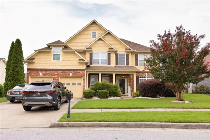 Two-story residence featuring a two-car garage, brick and siding exterior, and a prominent front entrance