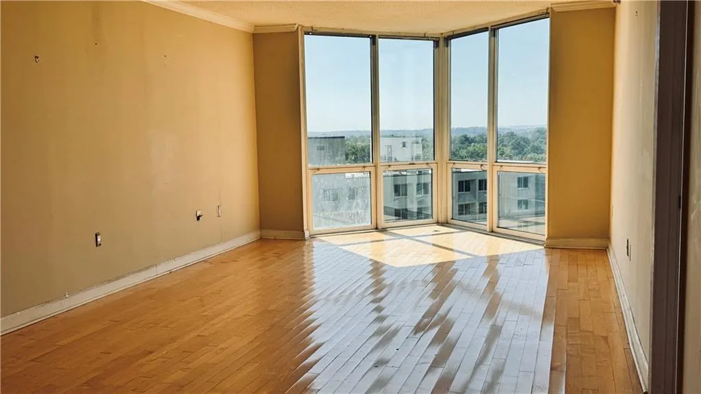 Empty room with expansive windows, light wood-style floors, and ornamental molding