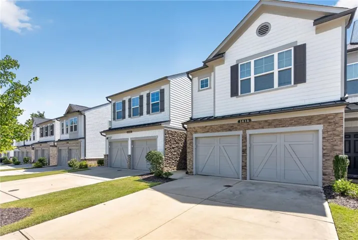 Contemporary exterior featuring white siding, dark shutters, and stone veneer accents