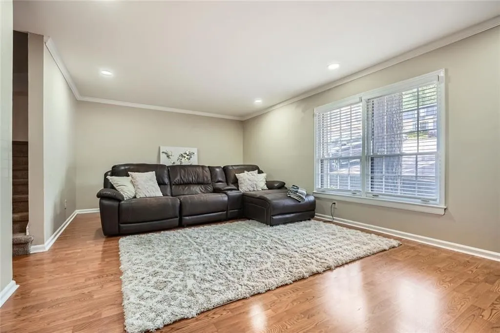 Living area featuring crown molding, light wood-type flooring, recessed lighting, and stairs