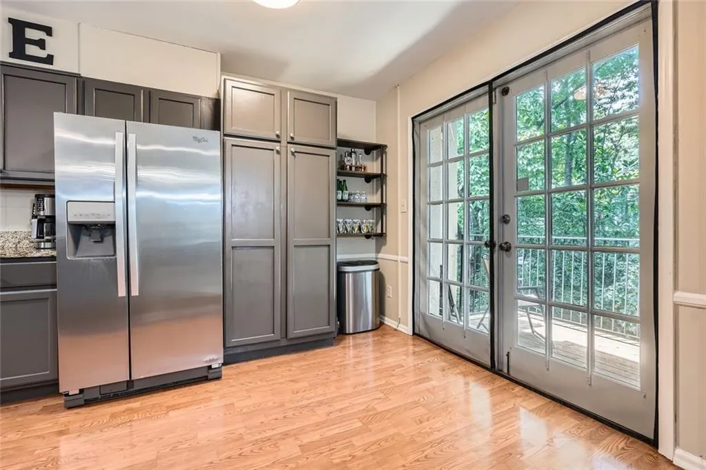 Kitchen featuring stainless steel refrigerator with ice dispenser, gray cabinetry, light wood-type flooring, and open shelves