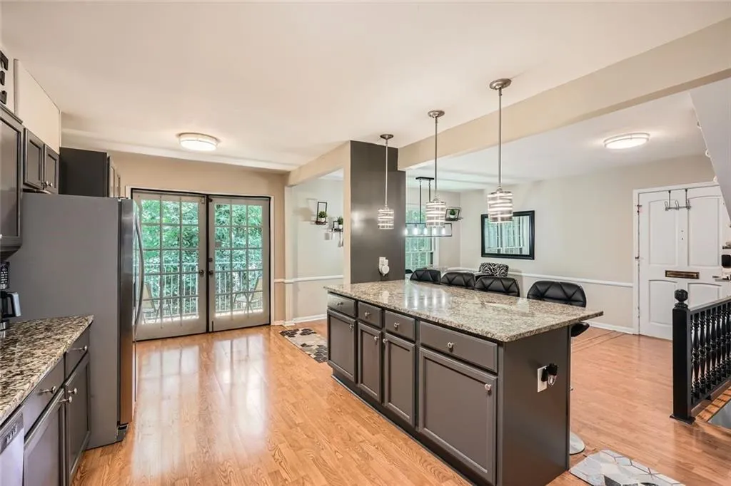 Kitchen with light stone counters, a kitchen bar, light wood-style floors, and plenty of natural light