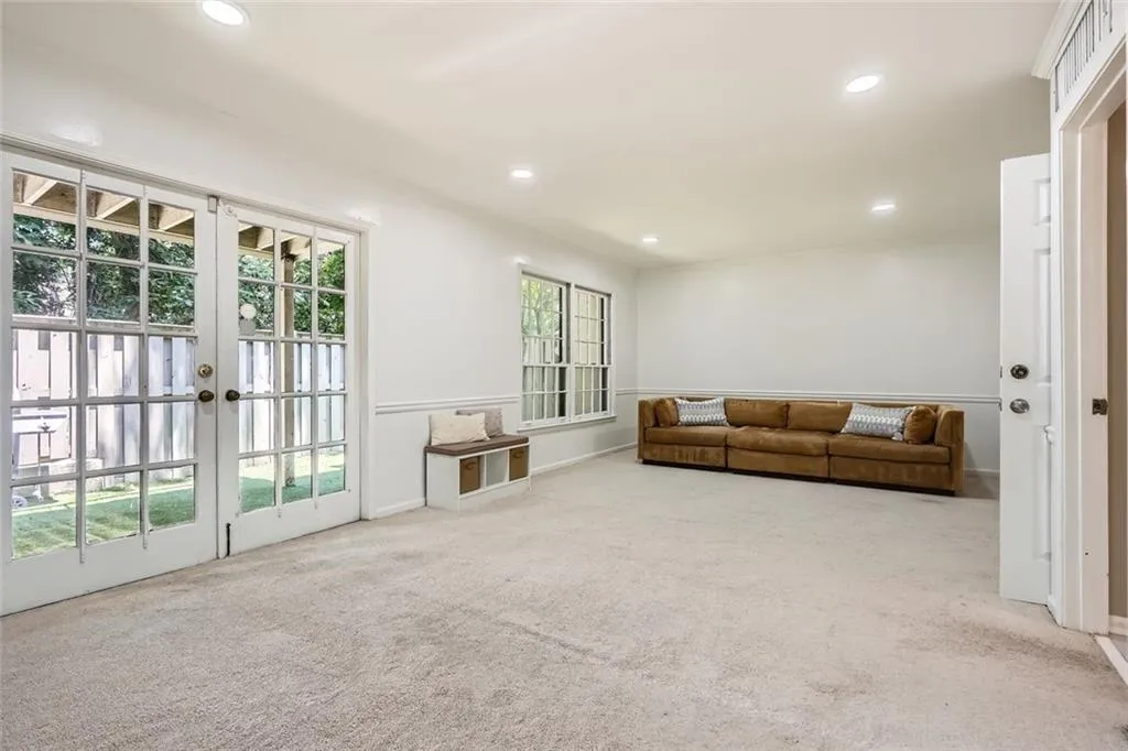 Living room with light colored carpet, recessed lighting, and french doors