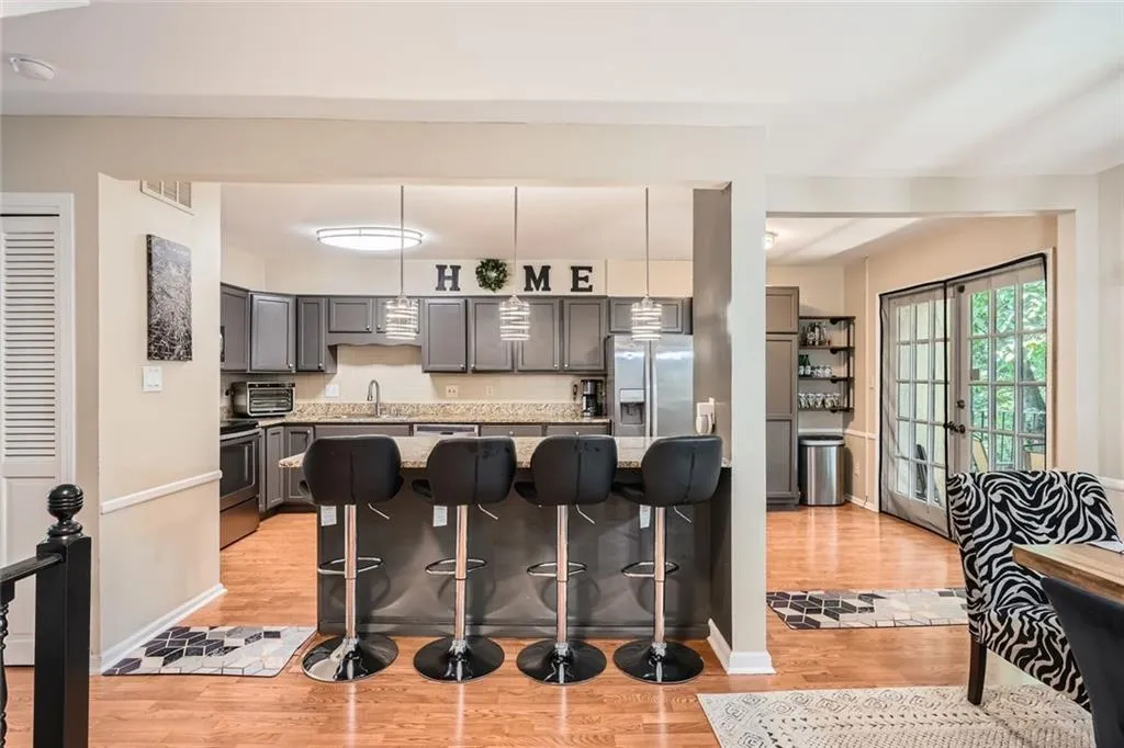 Kitchen featuring a kitchen breakfast bar, light wood-style floors, pendant lighting, gray cabinetry, and appliances with stainless steel finishes