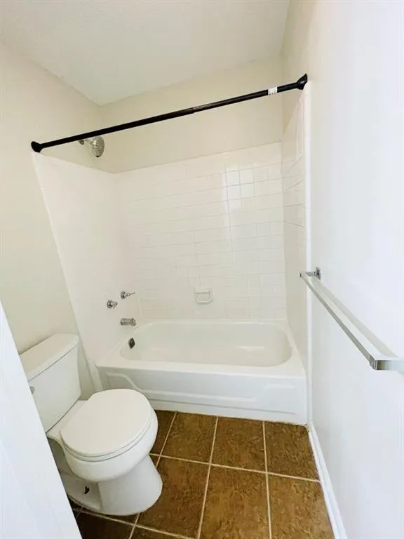 Full bath with toilet, tile patterned flooring, and bathing tub / shower combination