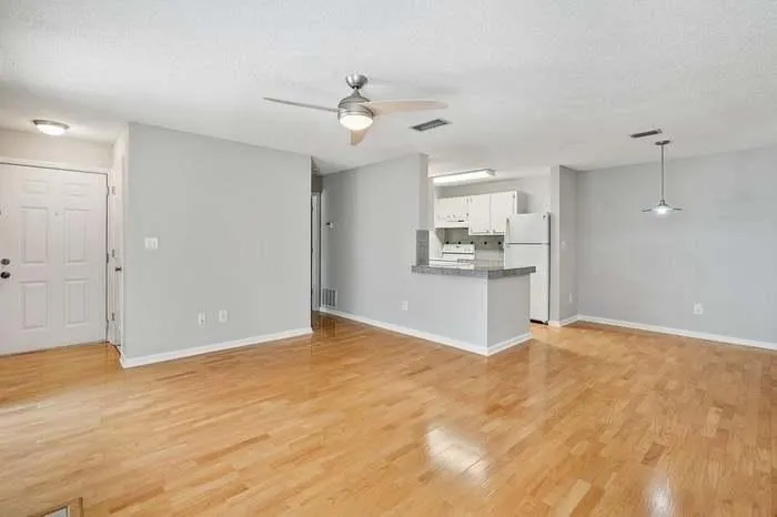 Unfurnished living room with light wood finished floors, baseboards, ceiling fan, and visible vents