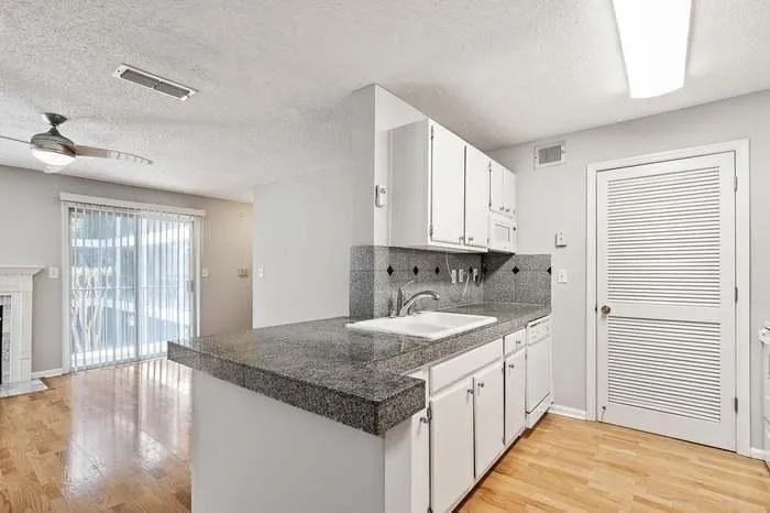 Kitchen featuring tile countertops, a sink, visible vents, and light wood-style floors