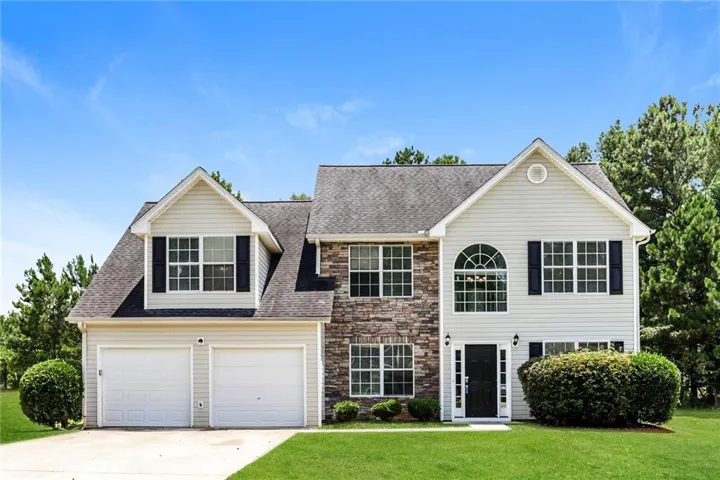 Two-story home with a two-car garage, stone and siding exterior, arched window, and prominent dormer