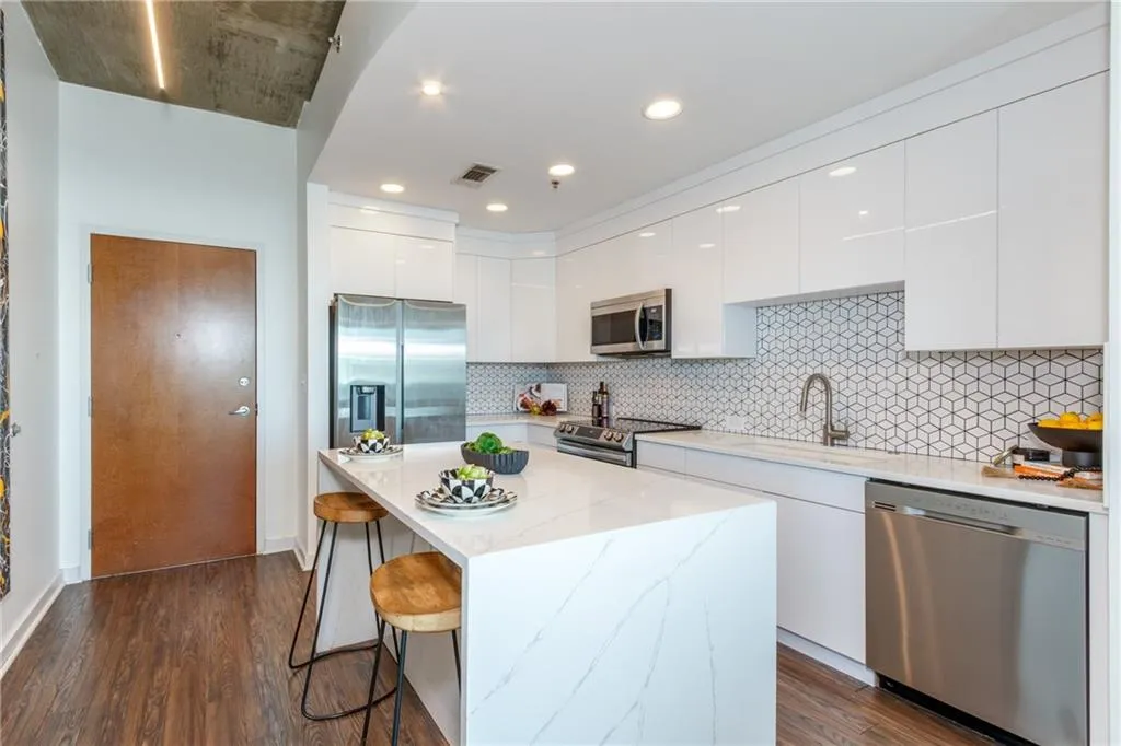 Kitchen with modern cabinets, stainless steel appliances, a kitchen bar, white cabinets, and dark wood-style flooring