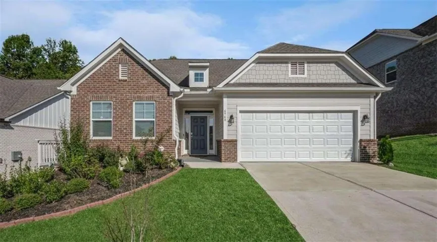 Attractive brick-front ranch-style home featuring a welcoming covered entry, two-car garage, manicured landscaping, and a spacious driveway for convenient parking.
