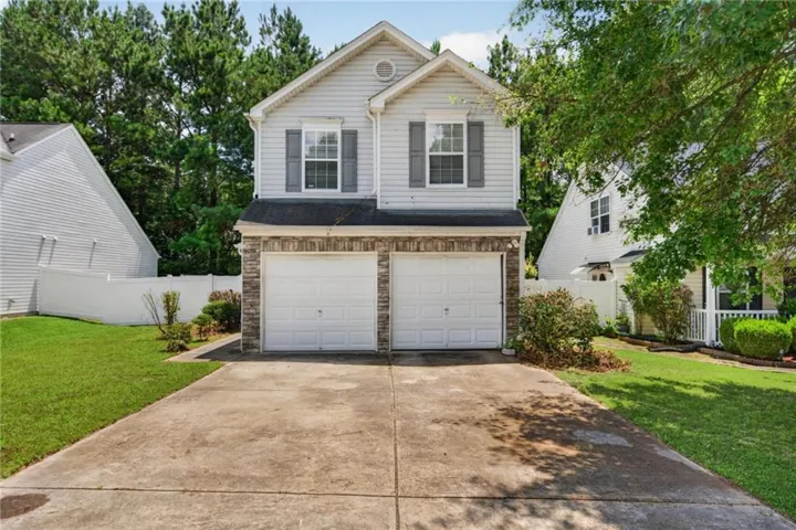 Two-car brick-front garage with white panel doors, positioned on a concrete driveway with clean geometric lines