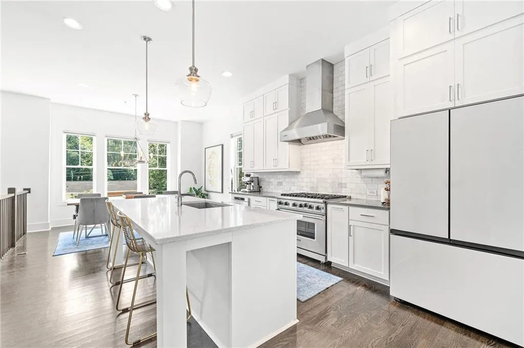 Kitchen featuring white fridge, wall chimney range hood, white cabinetry, high end stainless steel range oven, and decorative backsplash