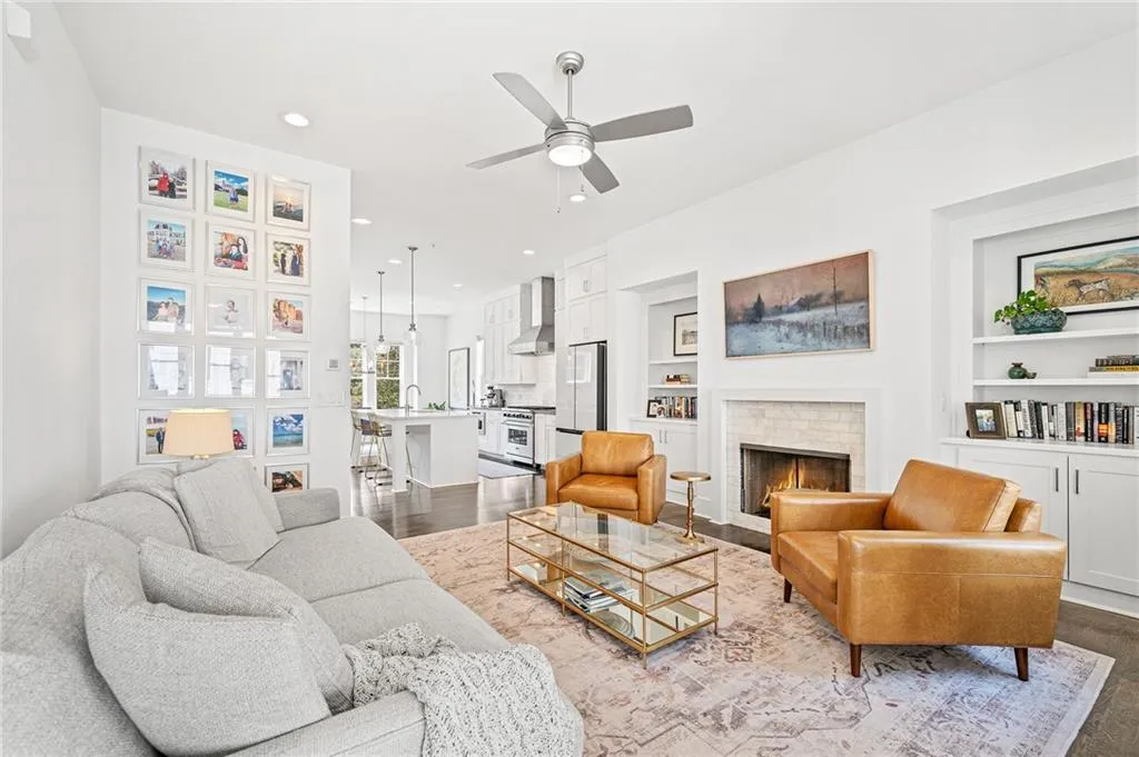 Living room with recessed lighting, a lit fireplace, dark wood-style floors, ceiling fan, and built in shelves