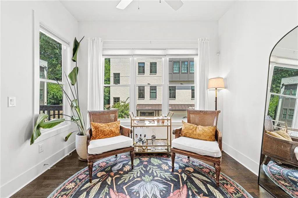 Sitting room with dark wood-style floors, healthy amount of natural light, and ceiling fan