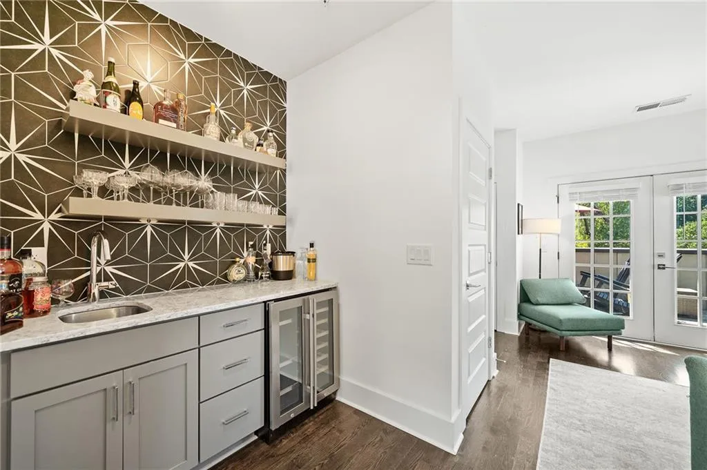 Indoor wet bar with light stone counters, open shelves, backsplash, dark wood-style floors, and beverage cooler