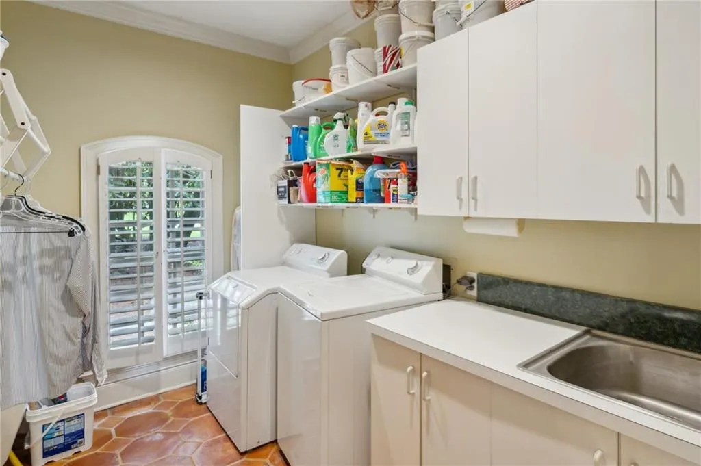 Laundry room with sink and cabinetry adjacent to kitchen