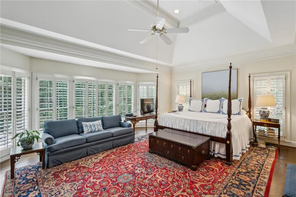 Large primary bedroom with tray ceiling and views of the pool