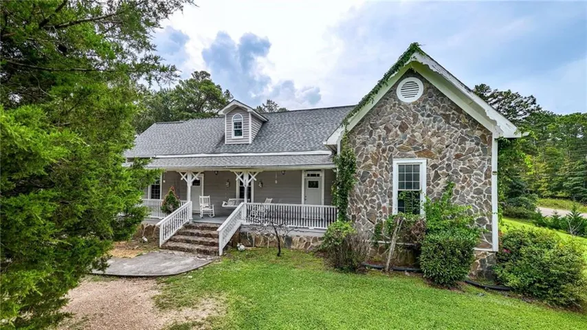 Stone and siding exterior with a covered porch, dormer window, and gabled roof