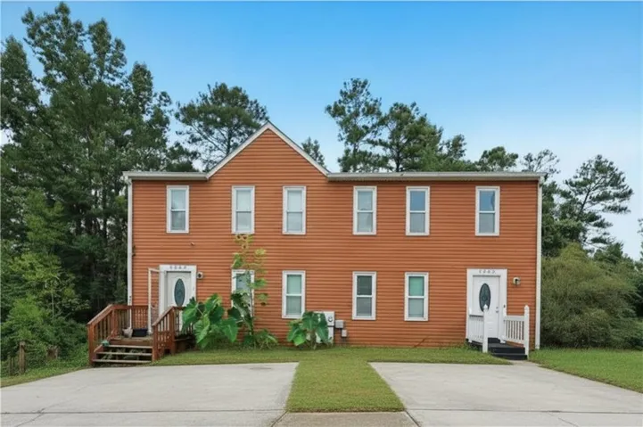 Two-story duplex with orange siding, multiple windows, and two distinct entrances