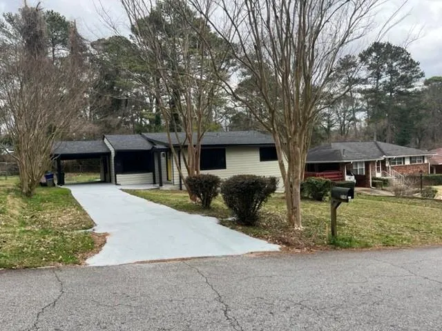 Ranch-style home featuring a front lawn and a carport