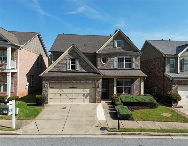 Two-story residence featuring a brick and siding facade, a two-car garage, and a covered front entry