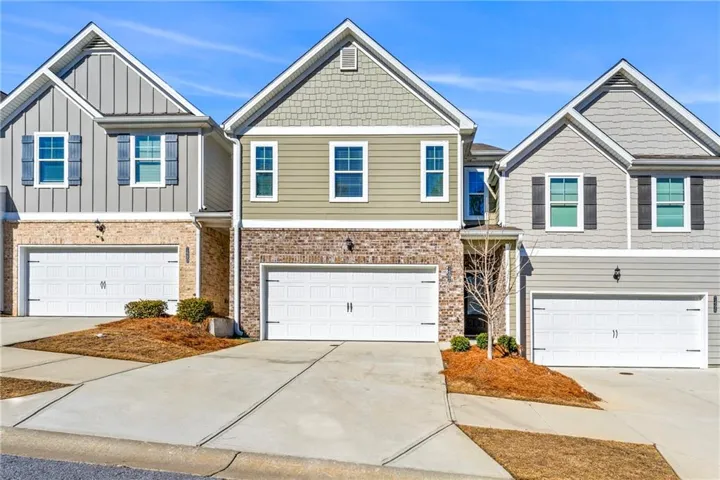 Multi unit property with brick siding, driveway, and a garage