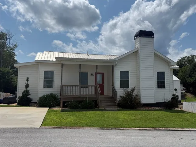 White siding exterior with a metal roof and a prominent chimney