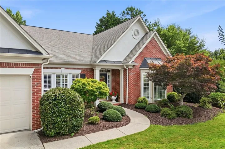 Red brick exterior with white trim, a gabled roofline, and an integrated garage