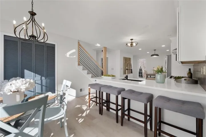 Open-concept kitchen with white cabinetry, a large island featuring a white countertop, and light wood-finish flooring