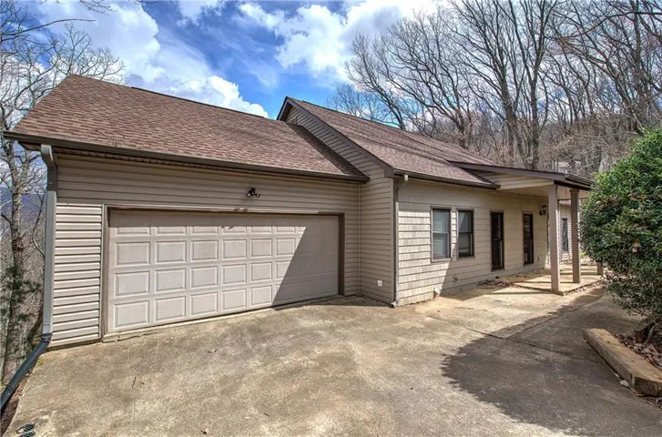 Exterior featuring horizontal siding, shake siding accents, an attached 2 car garage, a covered entry, and a paved driveway