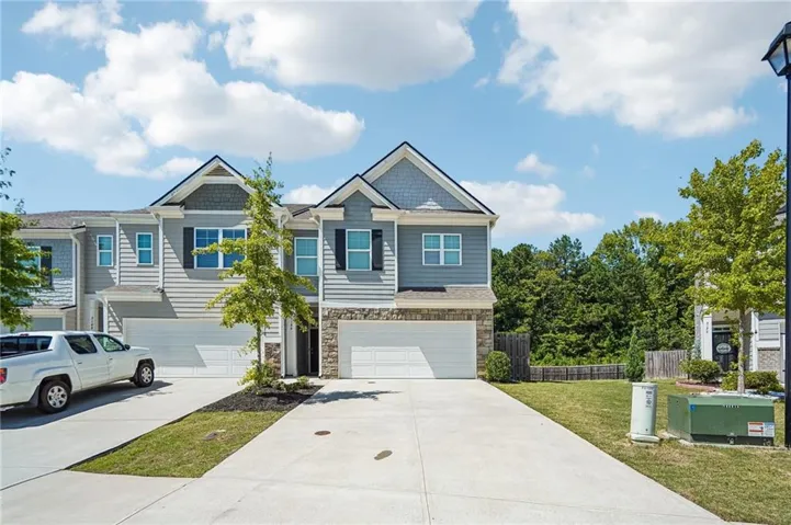 Townhome exterior featuring siding, stone accents, two-car garage, and a concrete driveway