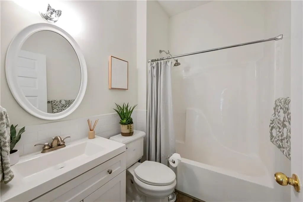 Full bath featuring vanity, shower / bathtub combination with curtain, backsplash, and tile walls