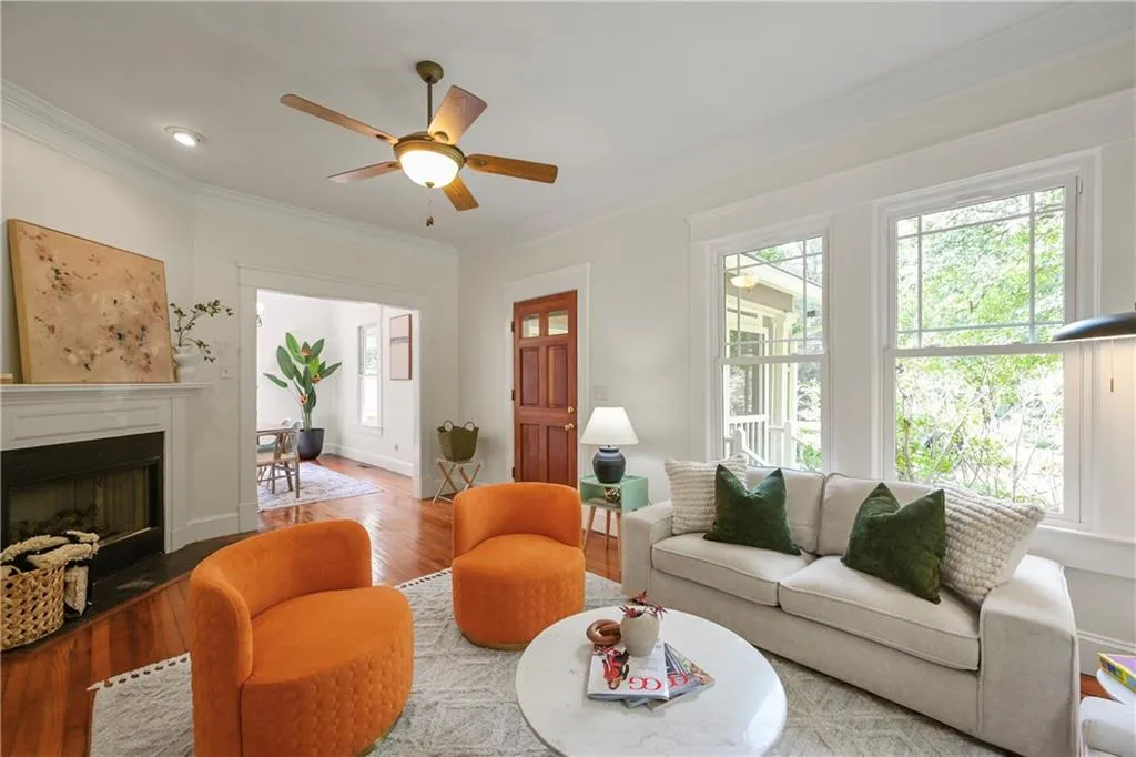Living area featuring ornamental molding, wood finished floors, a fireplace with flush hearth, and ceiling fan