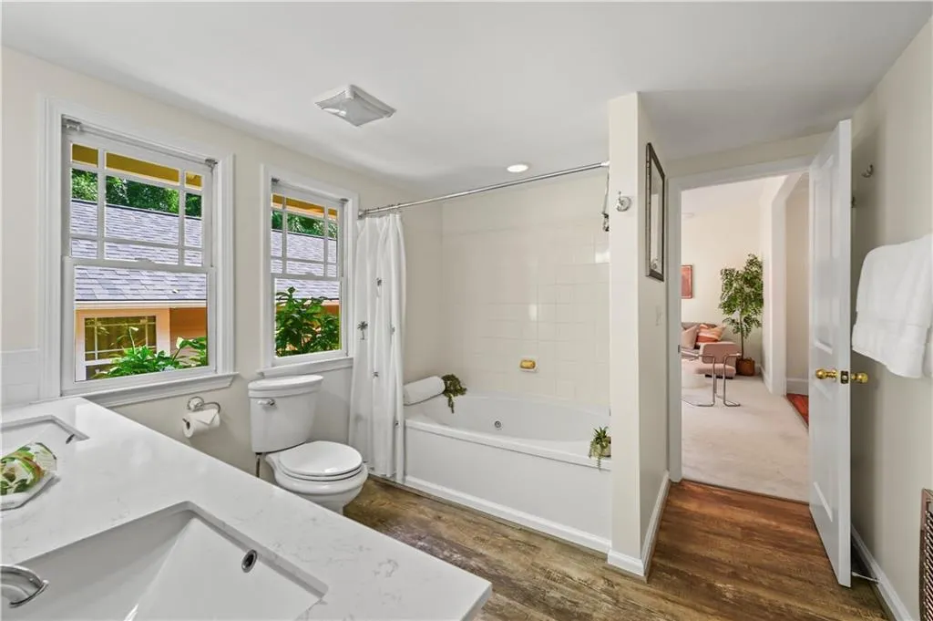 Full bath with shower / bathtub combination with curtain, dark wood-style flooring, and vanity