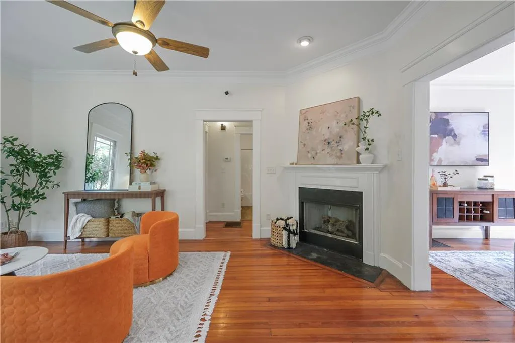 Living area with ornamental molding, hardwood / wood-style flooring, a fireplace with flush hearth, and ceiling fan