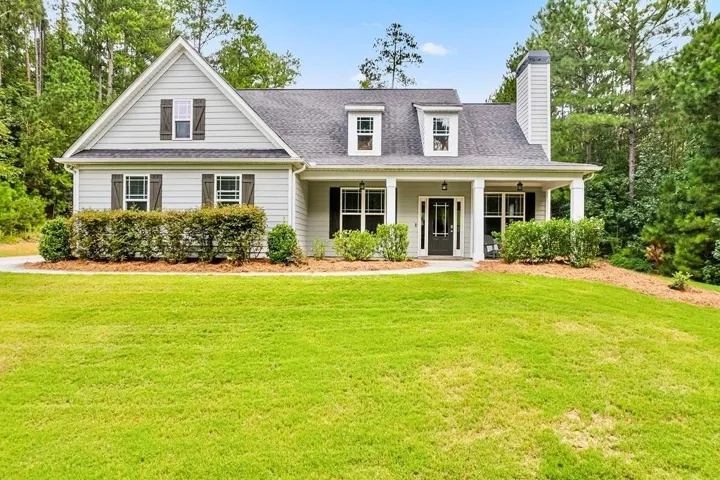 Classic Colonial-style residence featuring white fiber cement siding, a mansard roof with dormer windows, and a covered front portico with multiple columns