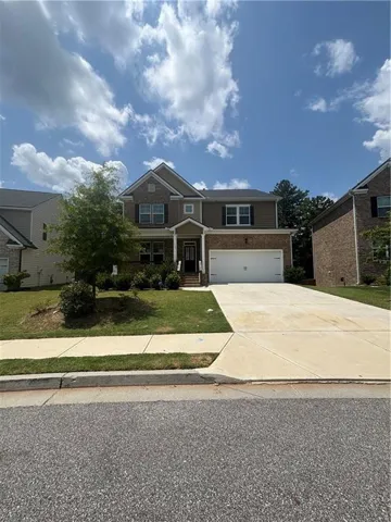 Two-story residence featuring a brick and siding facade, a covered front entry, a two-car garage, and a concrete driveway