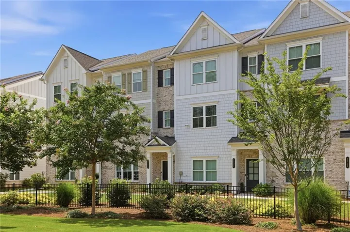 Three-story townhome with light-colored brick and horizontal siding