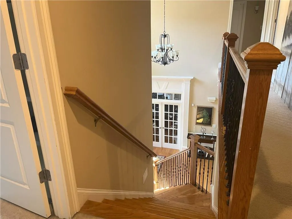 Stairway with a chandelier, wood finished floors, and a high ceiling